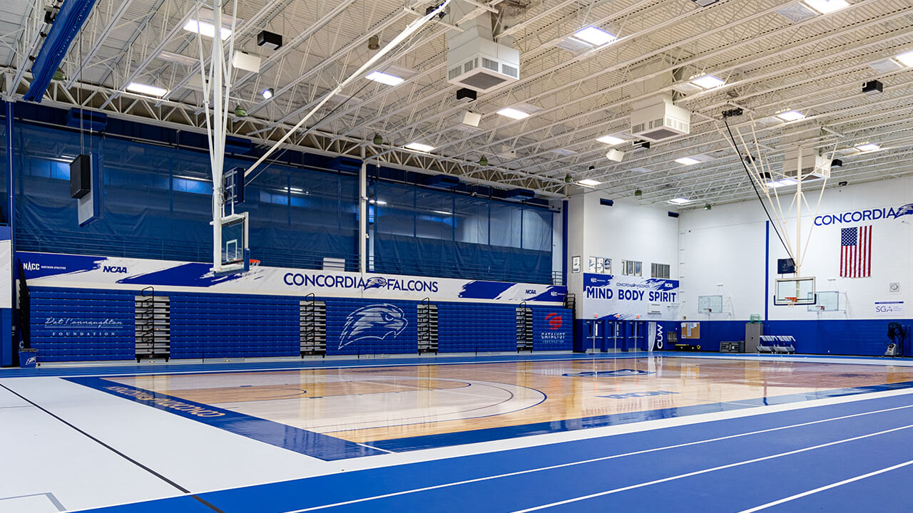 The newly renovated gymnasium with its mirror-like finish basketball floor, Lake Blue accent color, and Concordia Falcon logos.